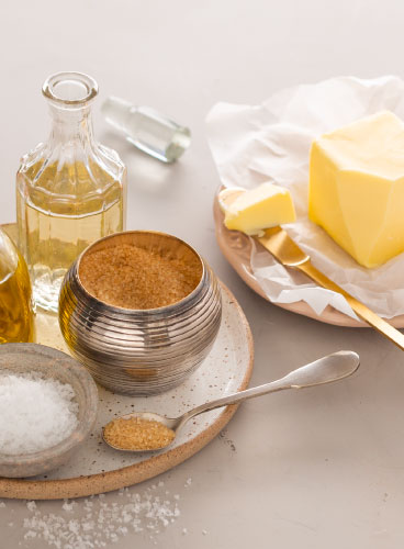 A imagem mostra manteiga e outros ingredientes que podem temperar alimentos, como sal, açúcar, azeite e vinagre.